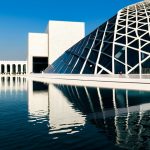 Architectural Marvel**

"The Louvre Abu Dhabi's stunning dome, bathed in sunlight creating dappled patterns on the white walls below, reflecting in the surrounding water.  Modern architecture blends seamlessly with the natural environment.  Fully clothed visitors stroll through the open spaces.  Safe for work, appropriate content, professional architectural photography, perfect anatomy, natural proportions, family-friendly, high quality."

**